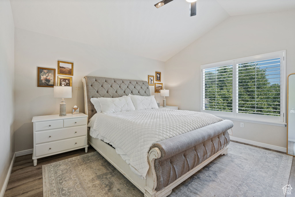 Bedroom featuring wood finished floors, baseboards, vaulted ceiling, and a ceiling fan