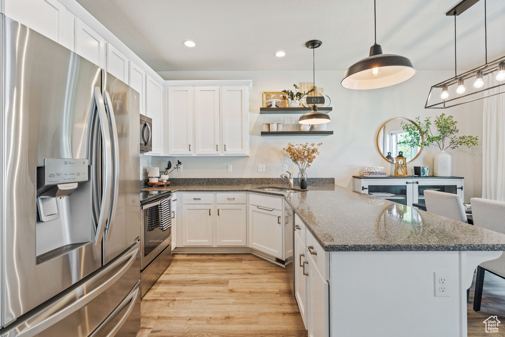 Kitchen with appliances with stainless steel finishes, a peninsula, white cabinetry, a sink, and recessed lighting