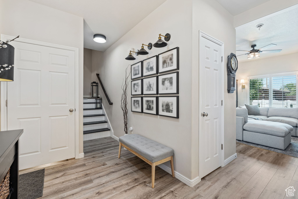Stairs with wood finished floors, ceiling fan, and baseboards