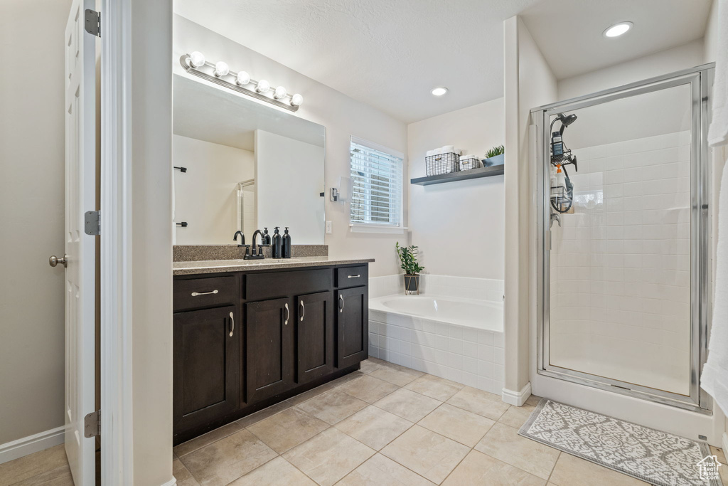Bathroom featuring vanity, a bath, a stall shower, and tile patterned floors