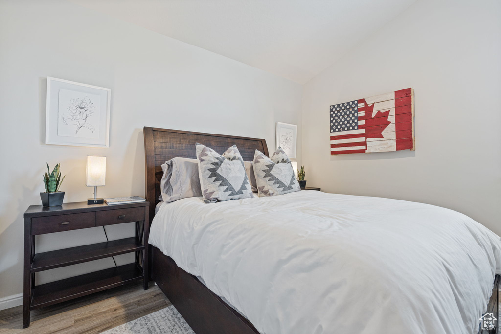 Bedroom featuring wood finished floors and lofted ceiling