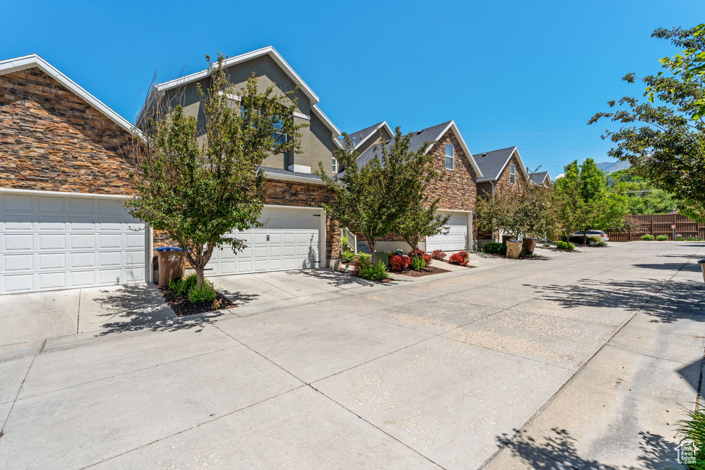 Obstructed view of property featuring concrete driveway, stone siding, and stucco siding
