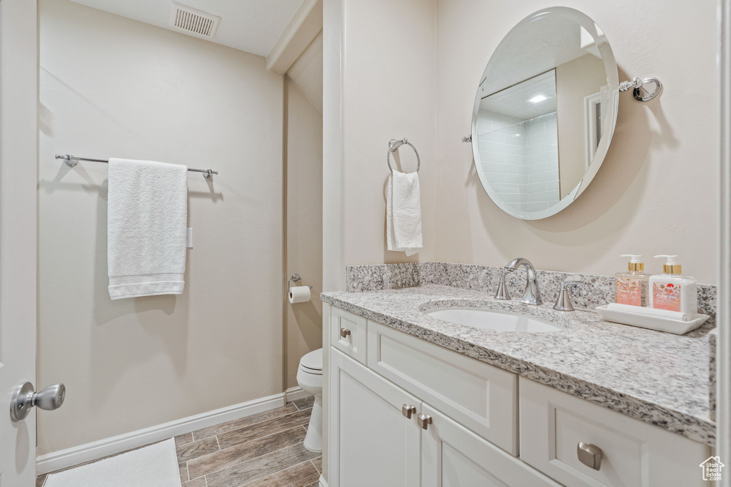 Full bathroom with vanity, toilet, wood finish floors, a shower, and baseboards