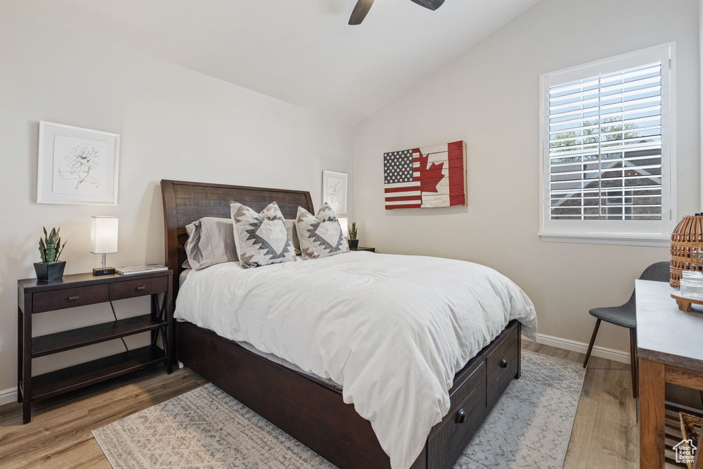 Bedroom featuring lofted ceiling, wood finished floors, baseboards, and ceiling fan