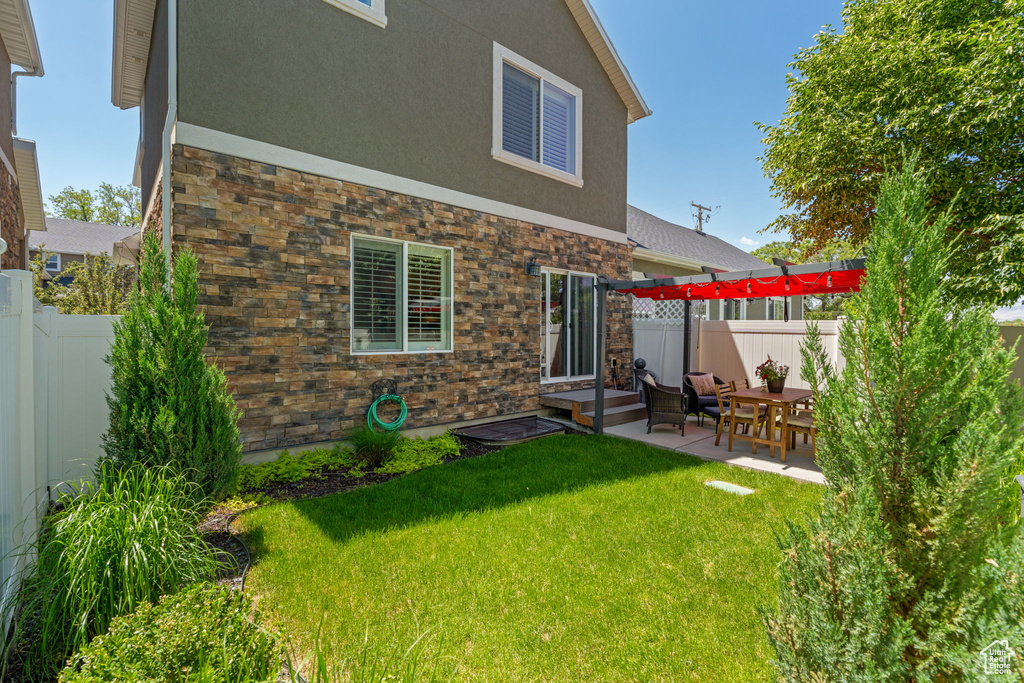 Rear view of property featuring stucco siding, stone siding, and a patio area