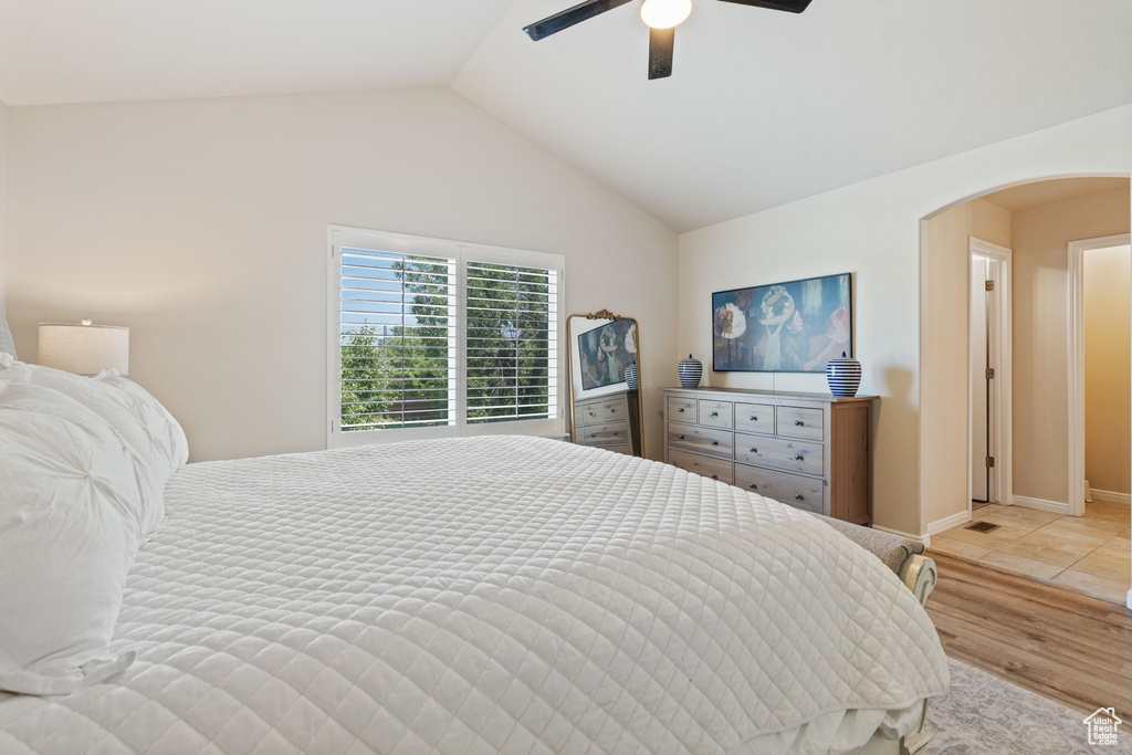 Bedroom with arched walkways, vaulted ceiling, a ceiling fan, and light wood finished floors