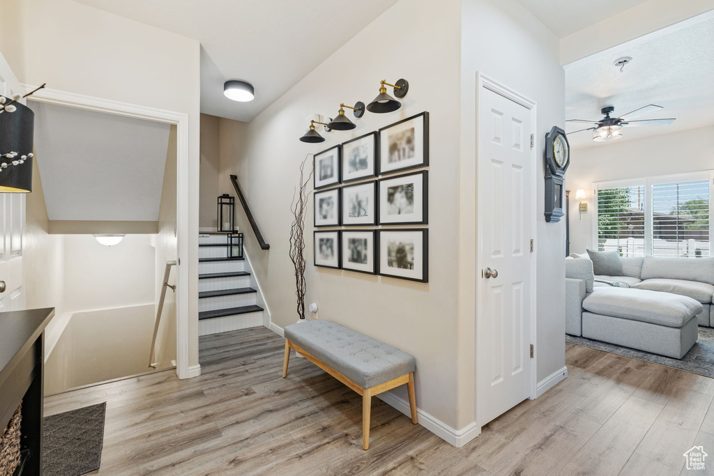 Stairs with wood finished floors, ceiling fan, and baseboards