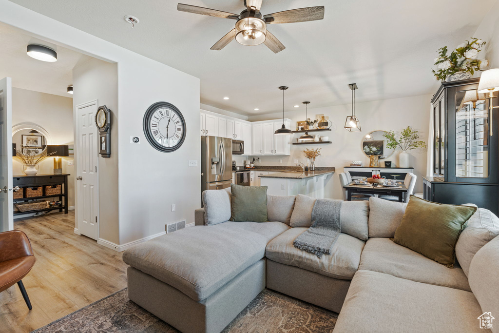 Living area with a ceiling fan, light wood-style floors, baseboards, and recessed lighting