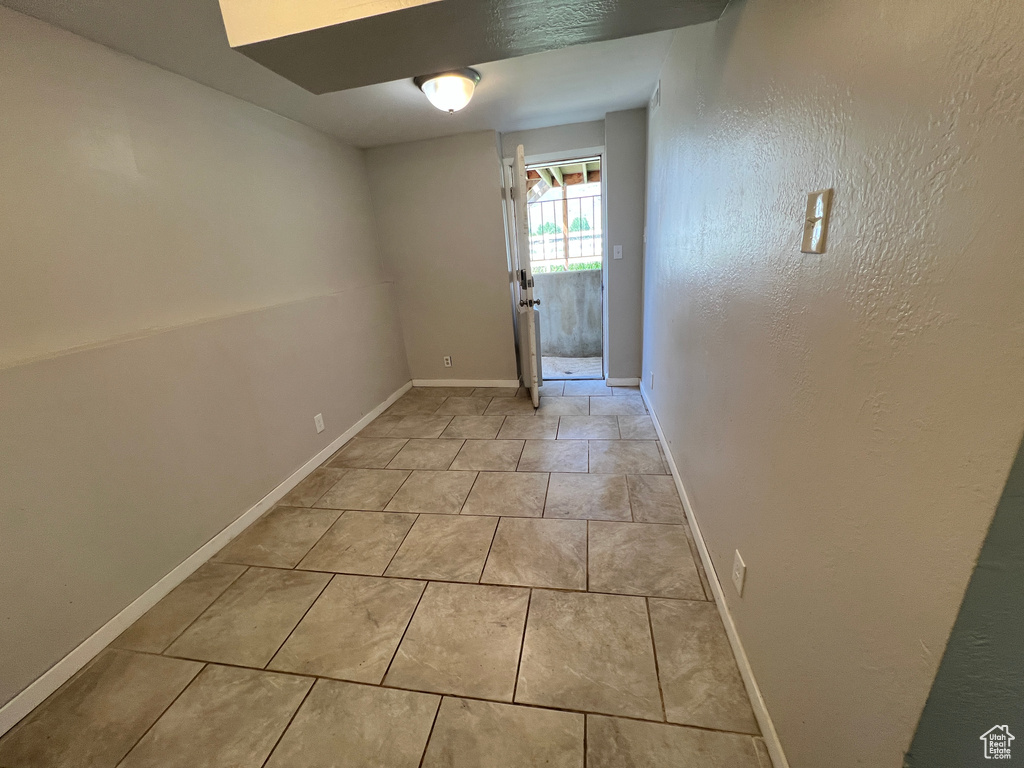 Unfurnished room featuring light tile patterned floors and baseboards