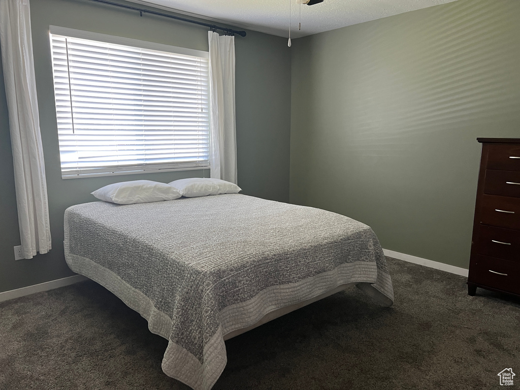 Bedroom with dark colored carpet and baseboards