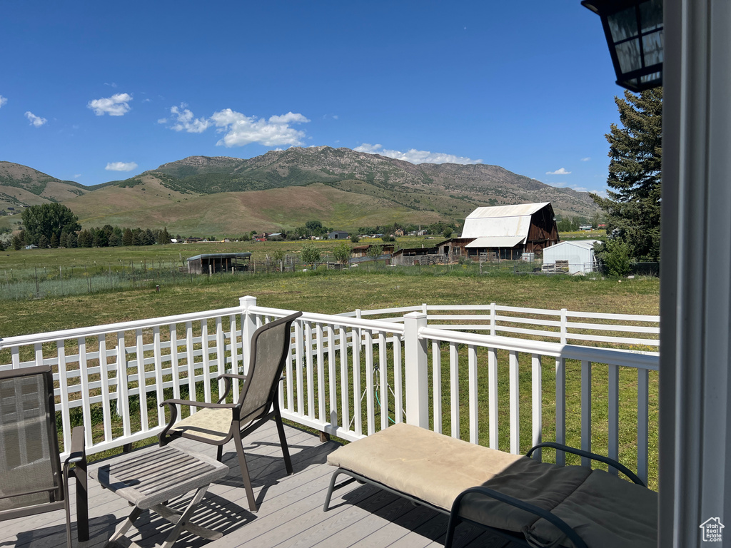 Wooden terrace featuring a mountain view, a yard, and a view of rural / pastoral area