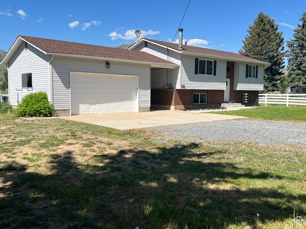 Raised ranch with concrete driveway and a garage