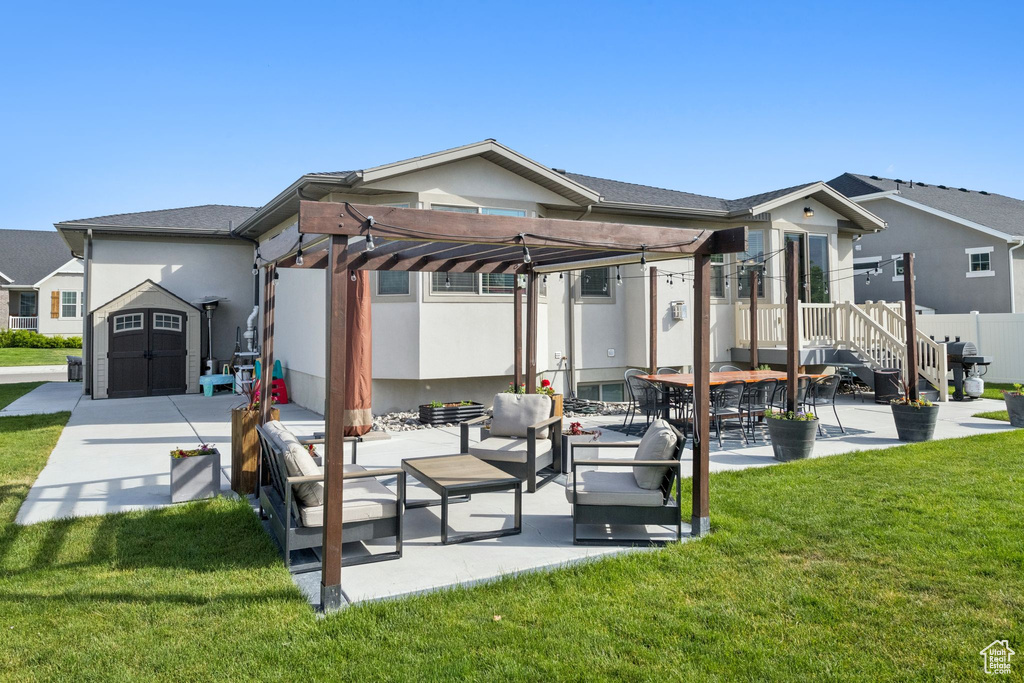 Back of property with a pergola, an outdoor living space, a patio, a yard, and stucco siding