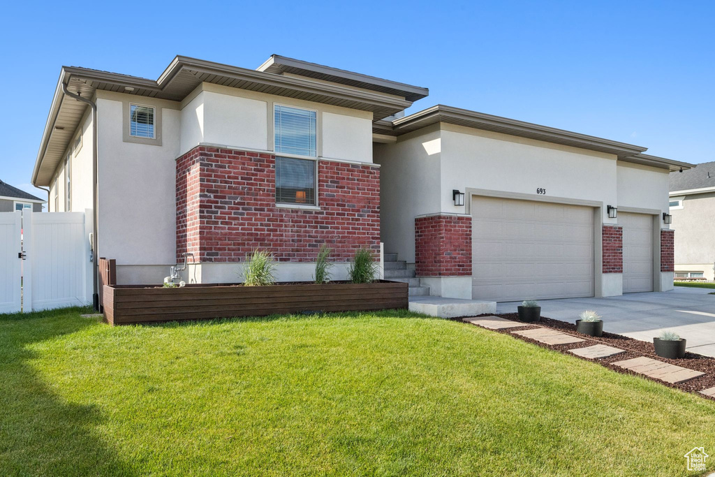 Prairie-style house with stucco siding, concrete driveway, brick siding, and an attached garage