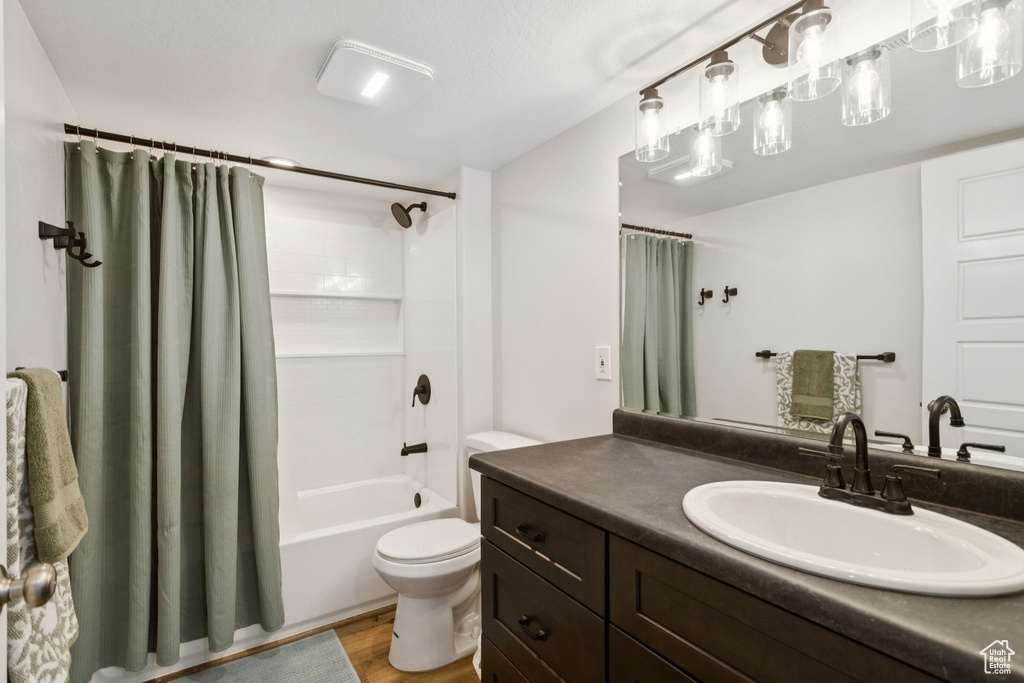 Full bathroom featuring vanity, toilet, shower / bath combo, and wood finished floors