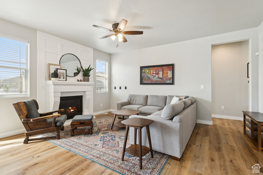 Living area featuring ceiling fan, wood finished floors, a large fireplace, and baseboards