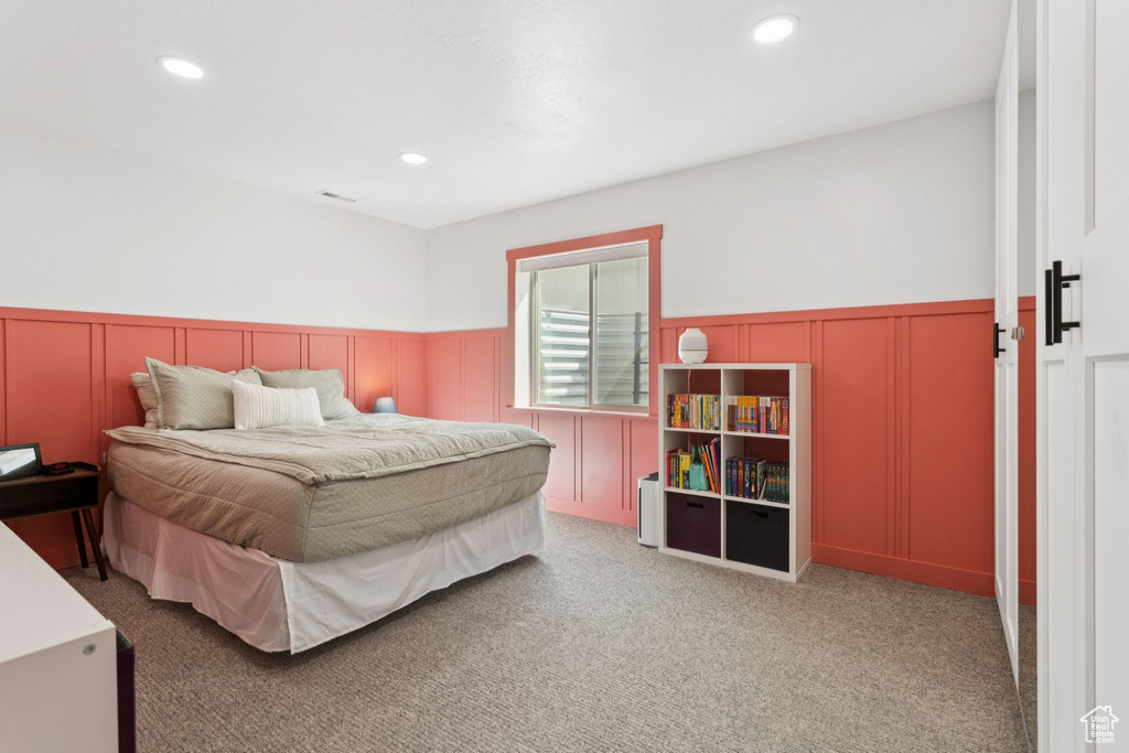 Bedroom with a decorative wall, wainscoting, recessed lighting, and carpet floors