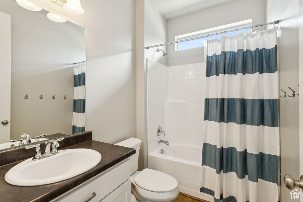 Bathroom with toilet, vanity, and shower / bath combination with curtain