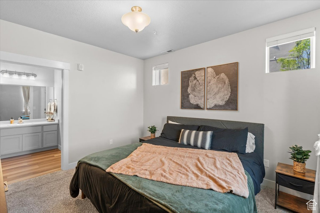 Bedroom featuring a sink, light wood-type flooring, connected bathroom, and baseboards