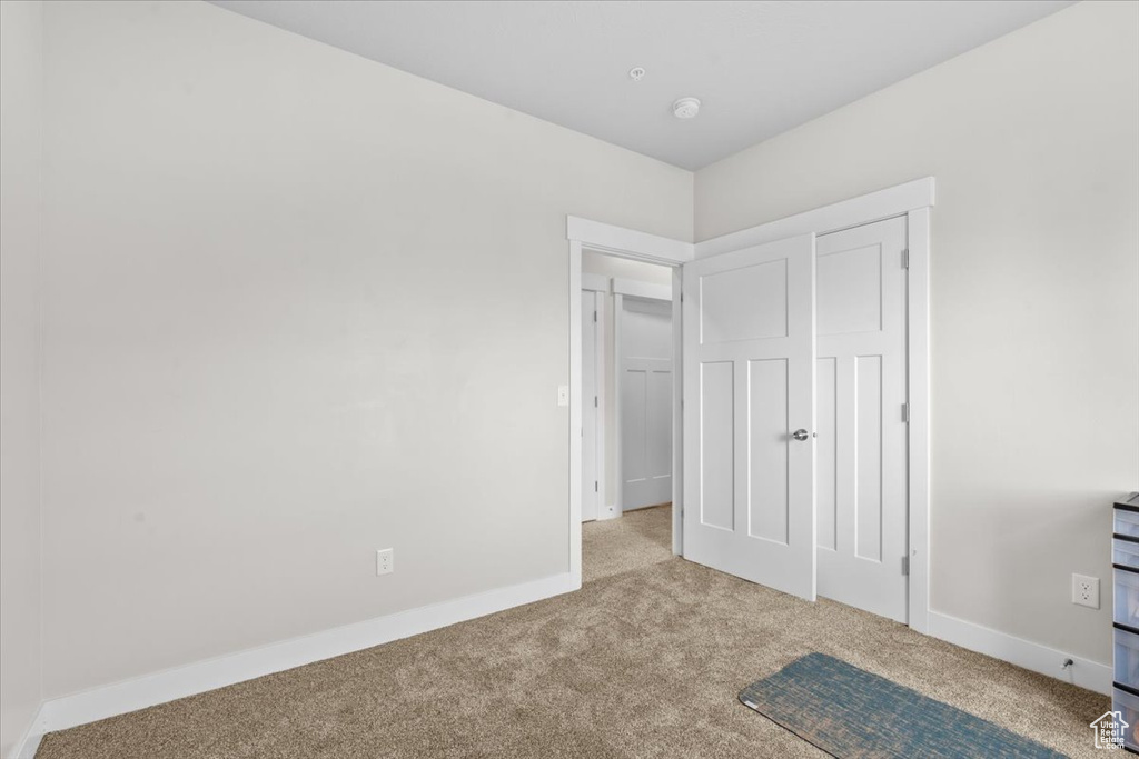 Unfurnished bedroom with carpet flooring and baseboards