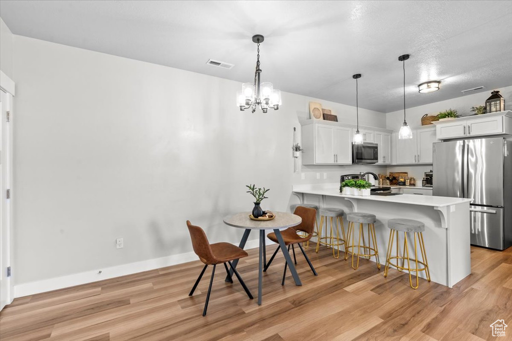 Kitchen with stainless steel appliances, light countertops, a breakfast bar, a peninsula, and light wood-type flooring