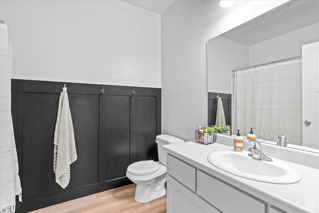 Full bath with vanity, toilet, and wood finished floors