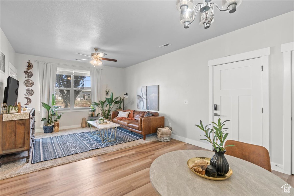 Living area with ceiling fan, wood finished floors, a chandelier, and baseboards