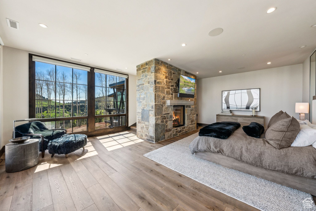 Bedroom featuring hardwood / wood-style flooring, a stone fireplace, floor to ceiling windows, and recessed lighting