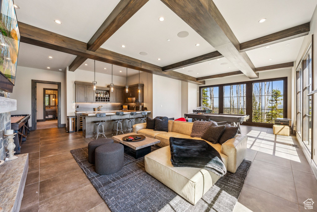 Living room with beamed ceiling, wet bar, dark tile patterned flooring, coffered ceiling, and recessed lighting