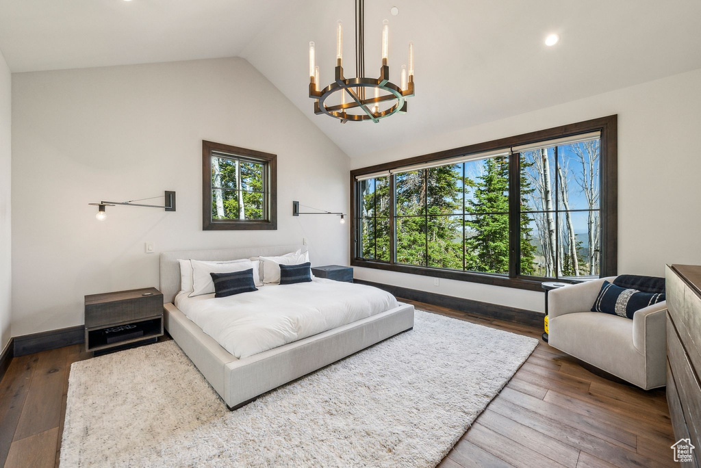 Bedroom with a chandelier, recessed lighting, wood finished floors, baseboards, and high vaulted ceiling
