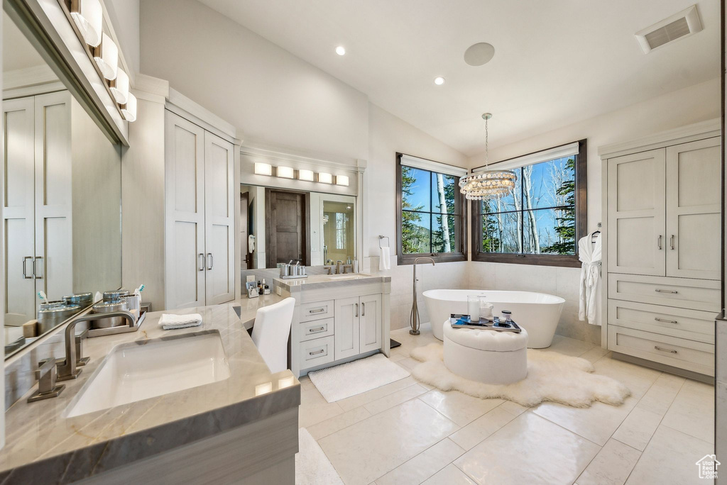 Full bathroom featuring vanity, lofted ceiling, a freestanding tub, a chandelier, and recessed lighting