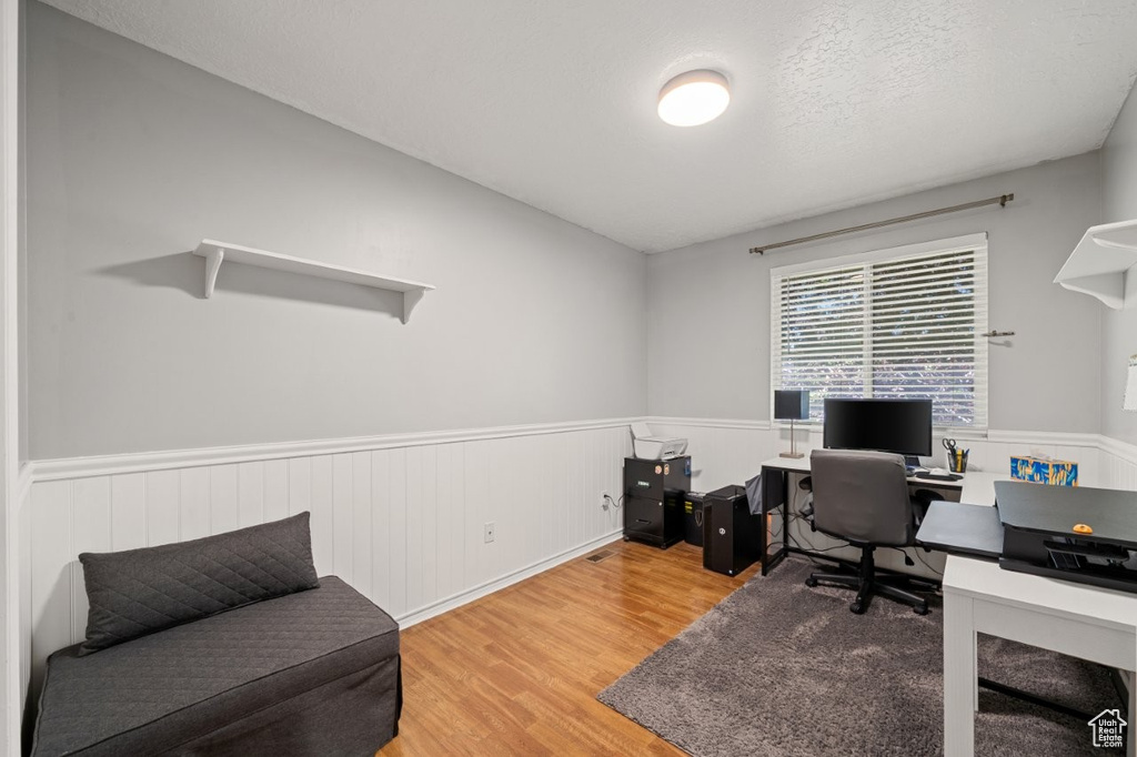 Home office featuring wood finished floors and a wainscoted wall