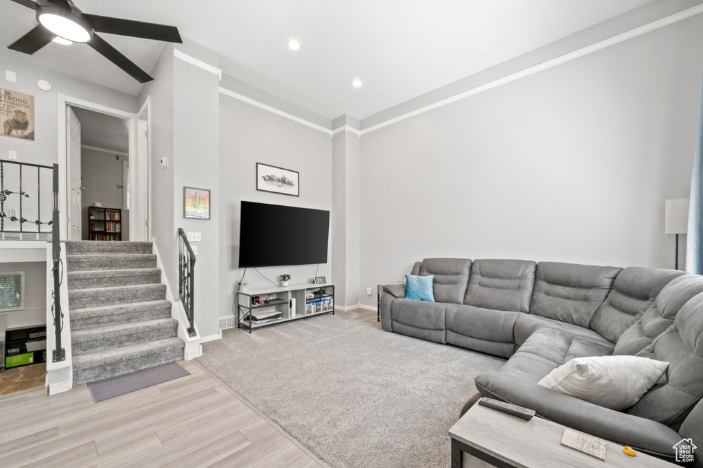 Living area with light wood-style floors, ceiling fan, baseboards, recessed lighting, and stairs