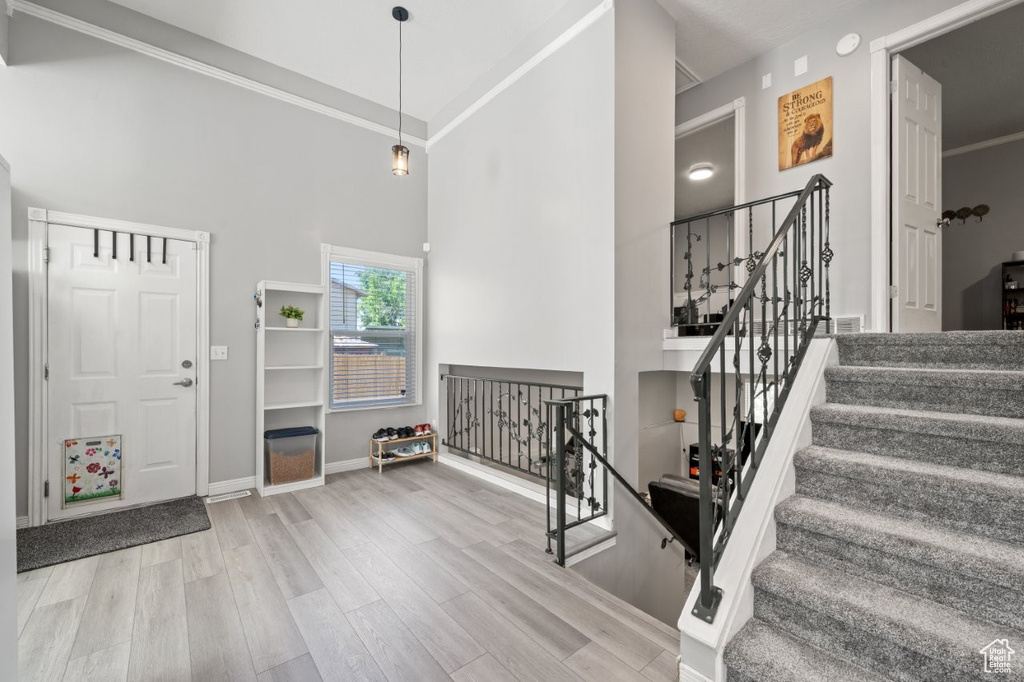 Entryway featuring a high ceiling, wood finished floors, baseboards, and ornamental molding
