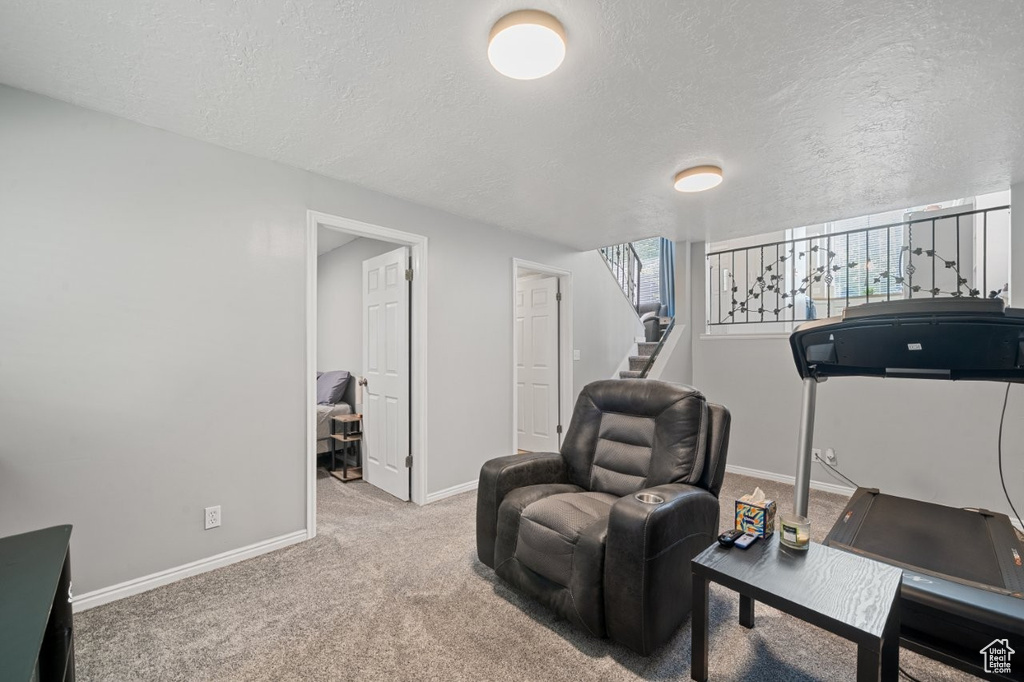 Sitting room featuring baseboards, a textured ceiling, carpet floors, and stairway