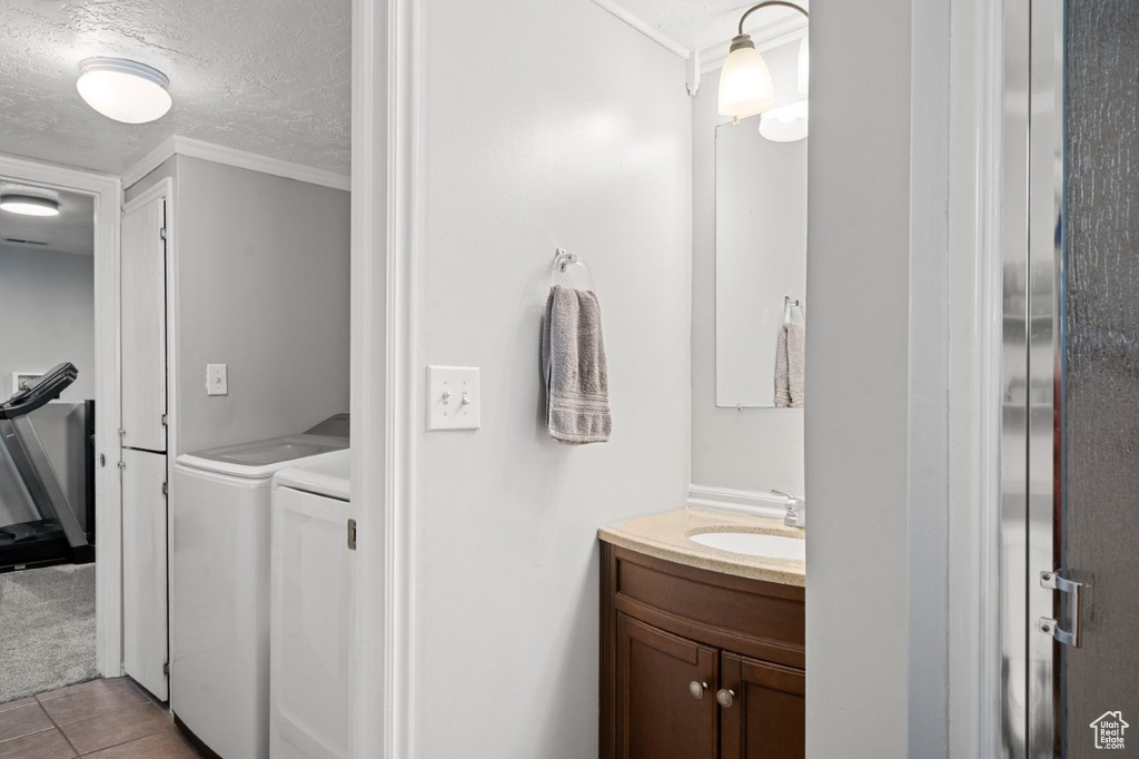 Bathroom with separate washer and dryer, vanity, ornamental molding, a textured ceiling, and tile patterned floors