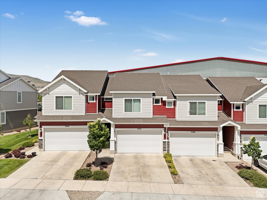 Multi unit property with a garage, concrete driveway, and a shingled roof