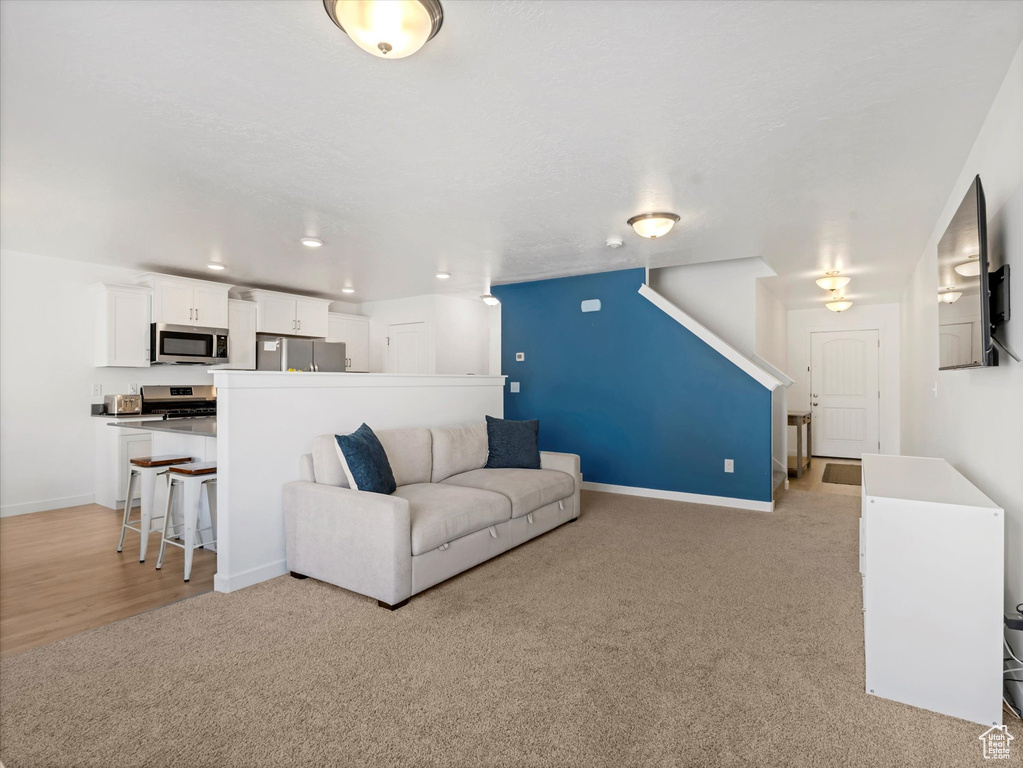 Living area with light colored carpet, baseboards, and recessed lighting