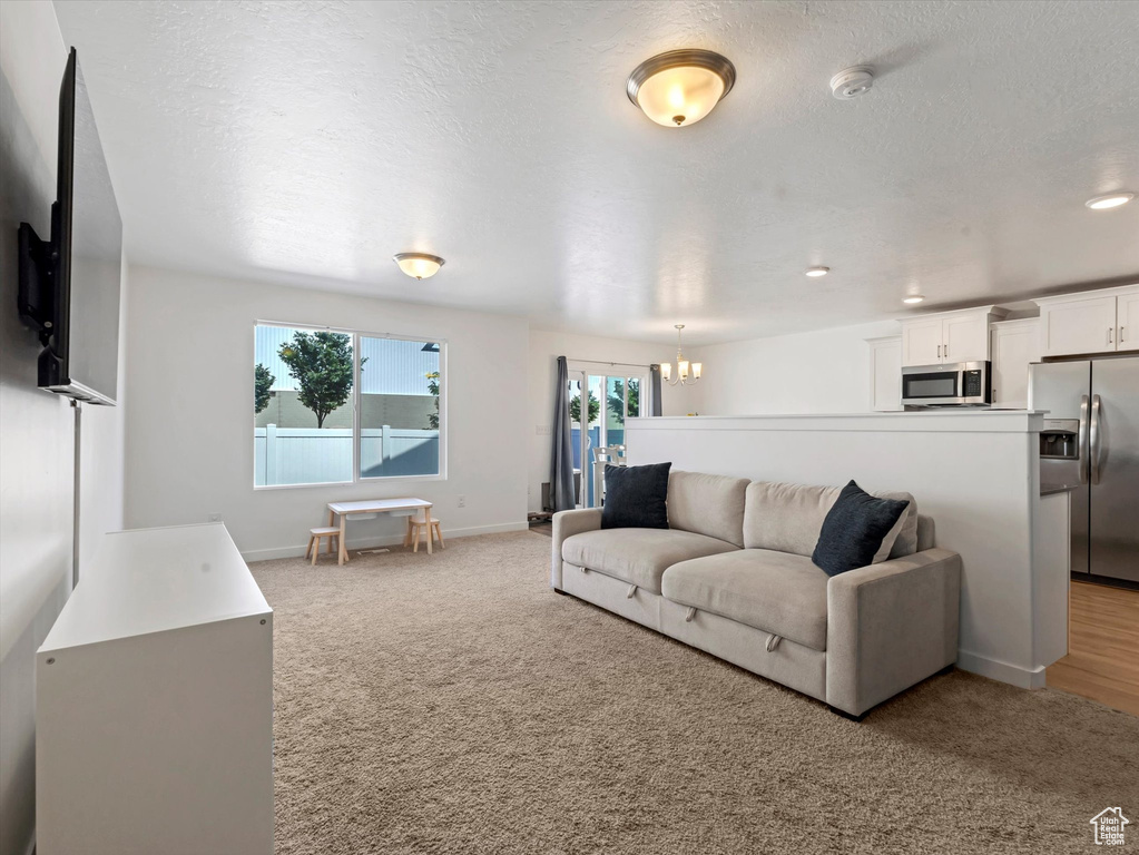 Living room with a chandelier, baseboards, light carpet, a textured ceiling, and recessed lighting