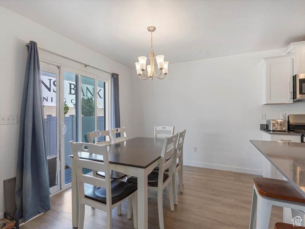 Dining area featuring a chandelier, light wood-style flooring, and baseboards