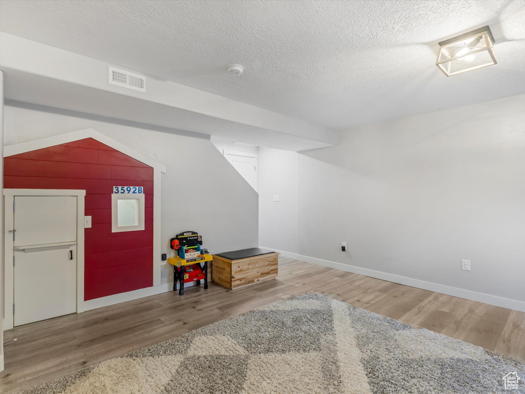 Finished basement with wood finished floors, a textured ceiling, and baseboards