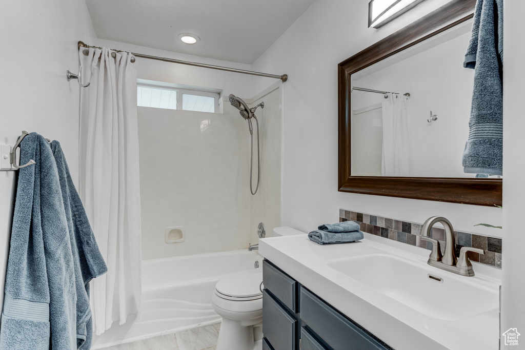 Full bathroom with vanity, shower / bathtub combination with curtain, and toilet