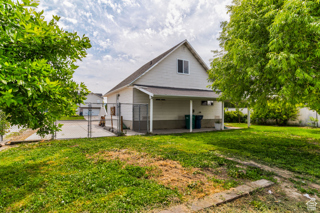 Back of house featuring a patio area, a gate, and a shingled roof