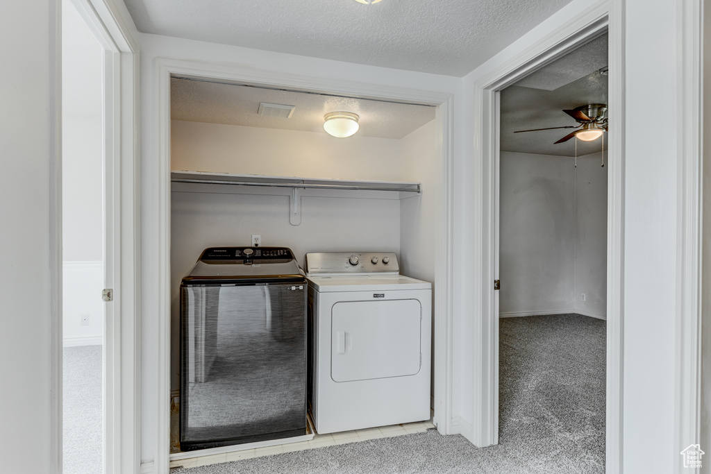 Washroom featuring separate washer and dryer, light carpet, and ceiling fan