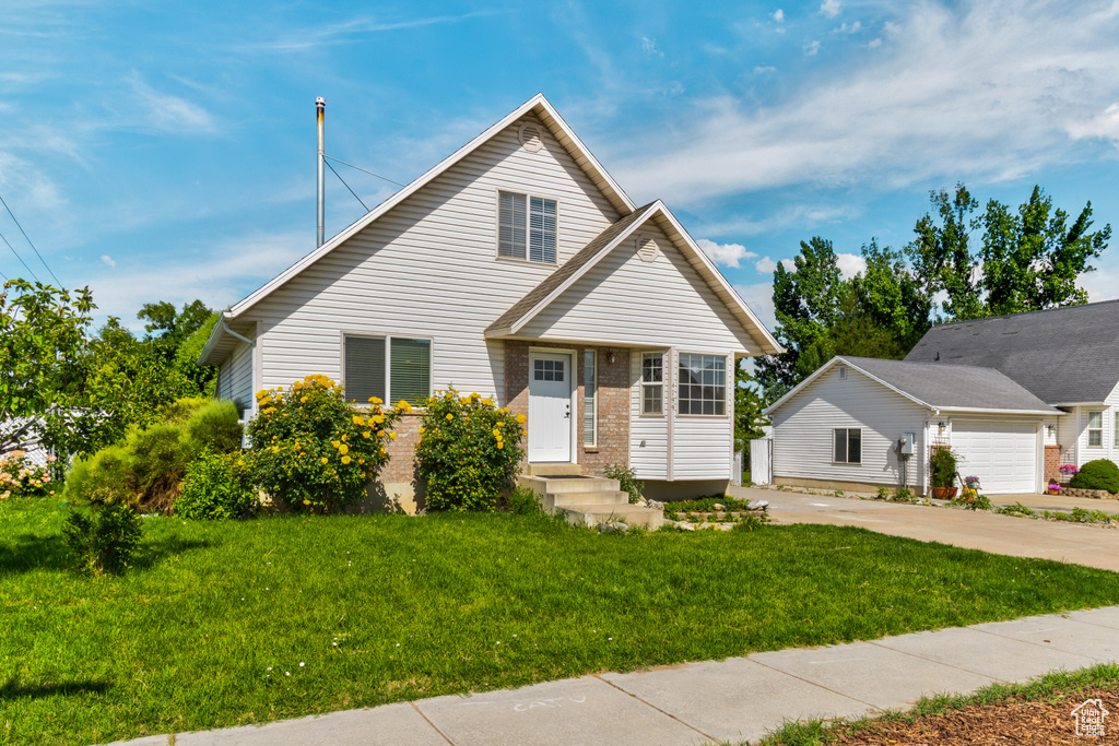 View of front facade with a front yard, brick siding, and driveway