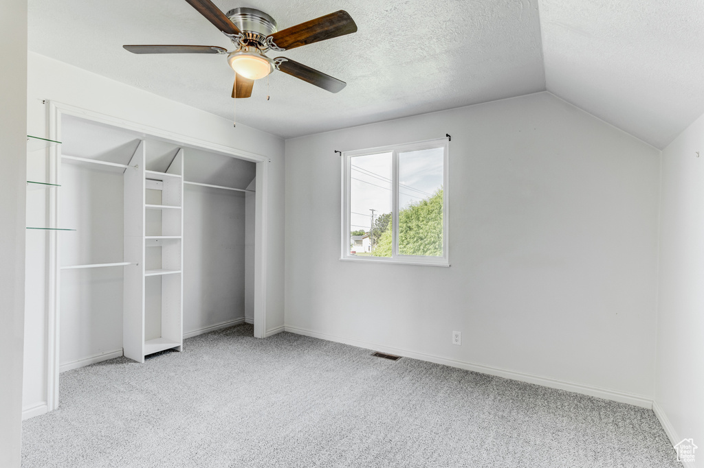 Unfurnished bedroom featuring carpet floors, lofted ceiling, a closet, baseboards, and a ceiling fan