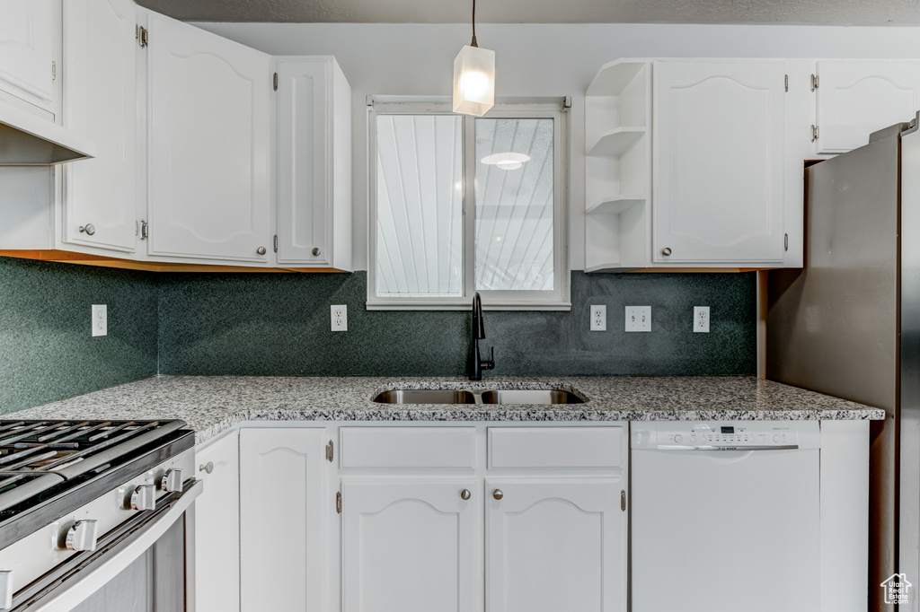 Kitchen with stainless steel appliances, a sink, tasteful backsplash, white cabinetry, and open shelves