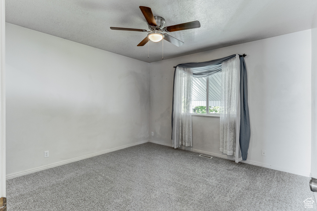 Empty room featuring a ceiling fan, carpet flooring, baseboards, and a textured ceiling