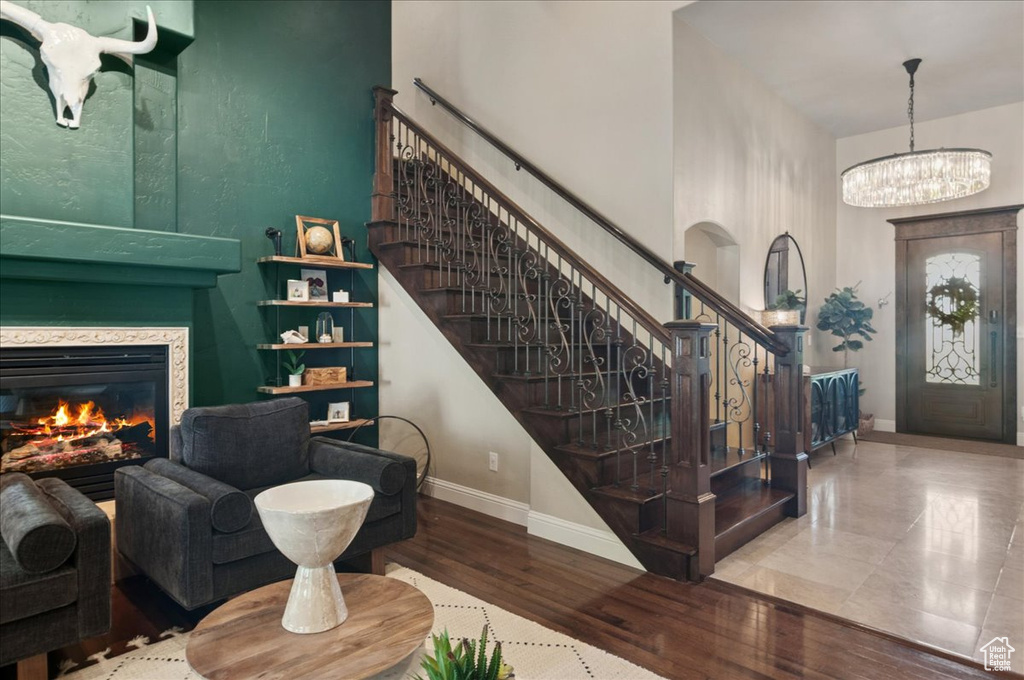 Foyer entrance featuring baseboards, stairway, a towering ceiling, wood finished floors, and a chandelier