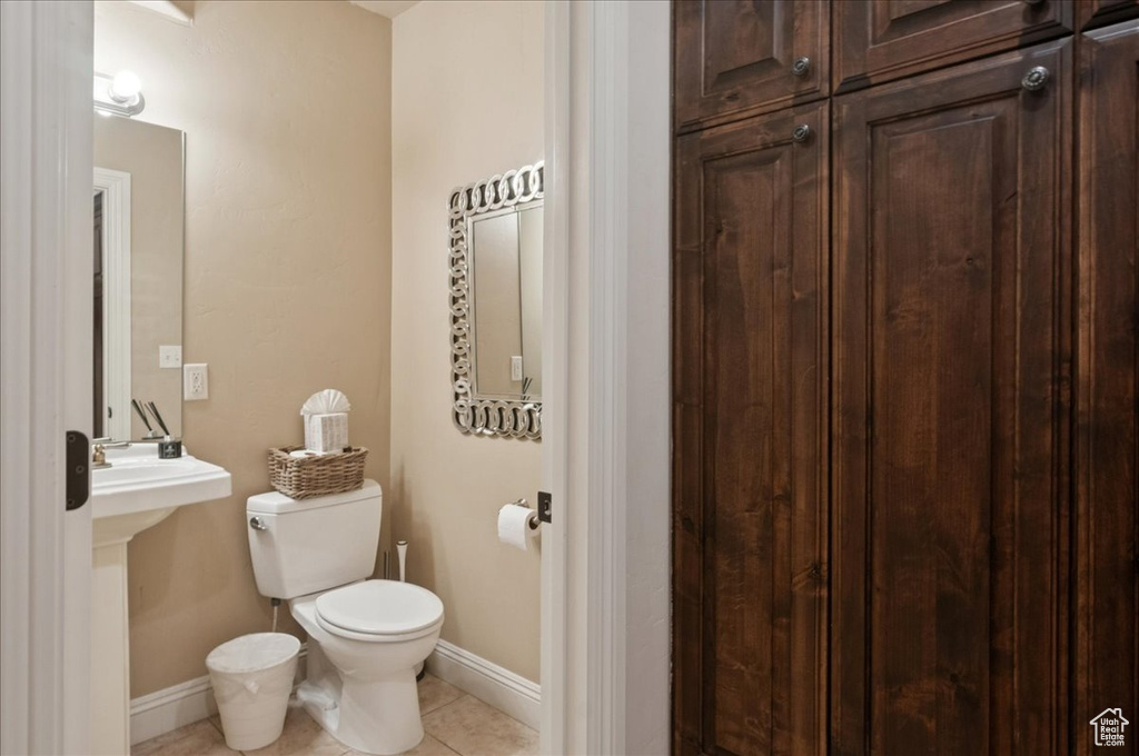 Half bath featuring toilet, tile patterned floors, and baseboards